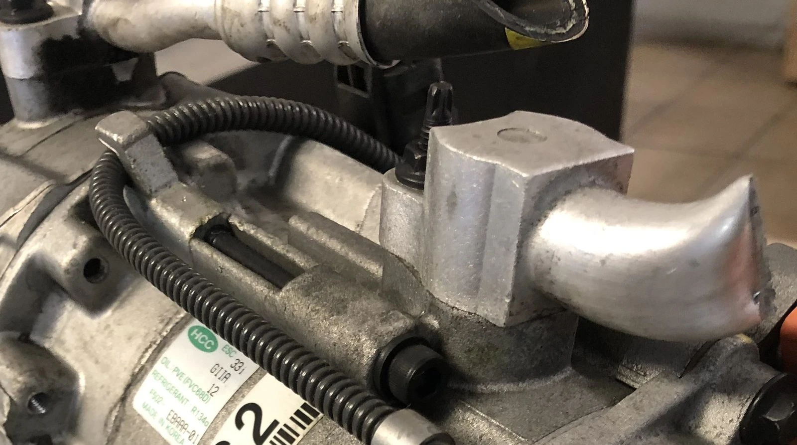 Close view of the port block and suction fitting on a removed AC compressor at Supercanic in Hemet