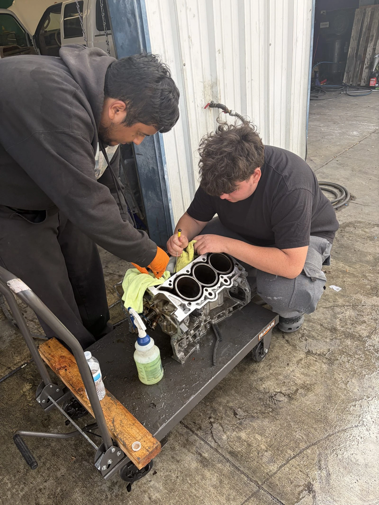 Two Supercanic mechanics prepping an engine block on the shop floor